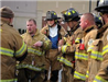 One fireman addressing group of firemen in uniform