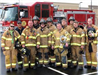 Group photo of eleven firemen in uniform in front of truck