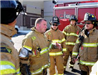 Fireman addressing group of firemen, all in uniform