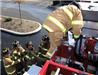 View from top of fire truck of four firemen handing hose from truck