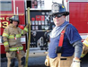 Two smiling uniformed firemen in front of fire truck