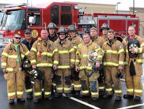 Group photo of eleven firemen in uniform in front of truck