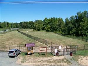 Aerial image of fenced in field, with a car in a parking lot