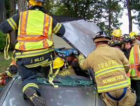 Firemen working to remove windshield of vehicle