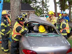 Firemen using jaws of life to open vehicle and remove victim