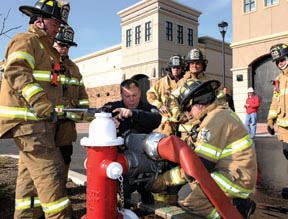 Firemen attaching red fire hose to red fire hydrant